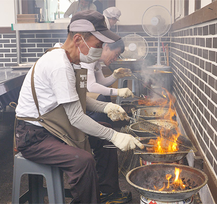 연탄불고기를 조리중인 앞치마를 입은 사람들